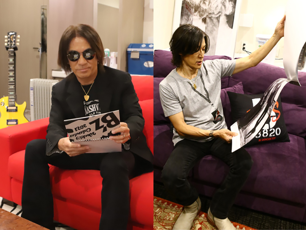 Zepp Haneda（TOKYO）の楽屋で「B'zカレンダー2021」を確認する松本孝弘と稲葉浩志の写真